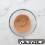 Instant Monkey Bread Delight 8 The cinnamon-sugar mixture in a glass bowl, prepared for coating the biscuits.