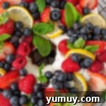 Finished lemon angel food cake adorned with whipped cream and fresh berries on a wire rack.