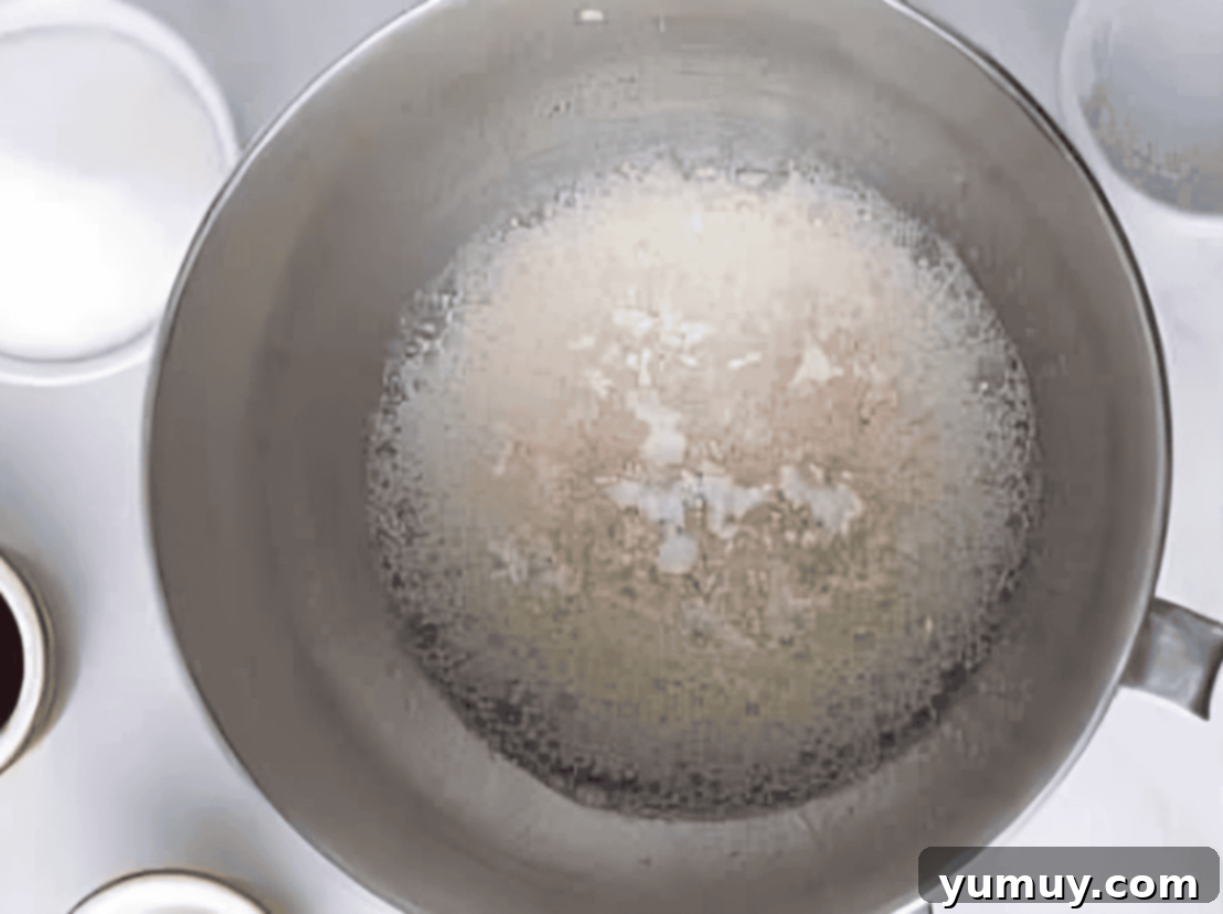Cream of tartar and kosher salt added to partially whipped egg whites in a stainless steel mixing bowl.