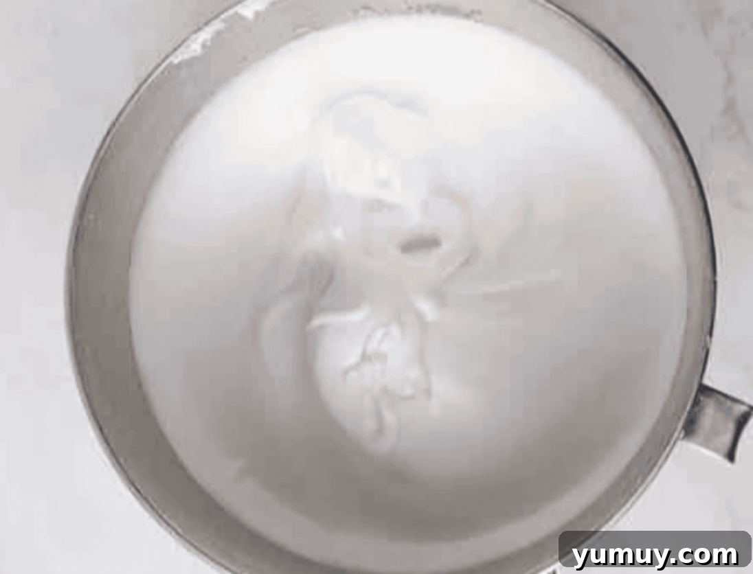 A stainless steel mixing bowl filled with perfectly whipped, stiff meringue.