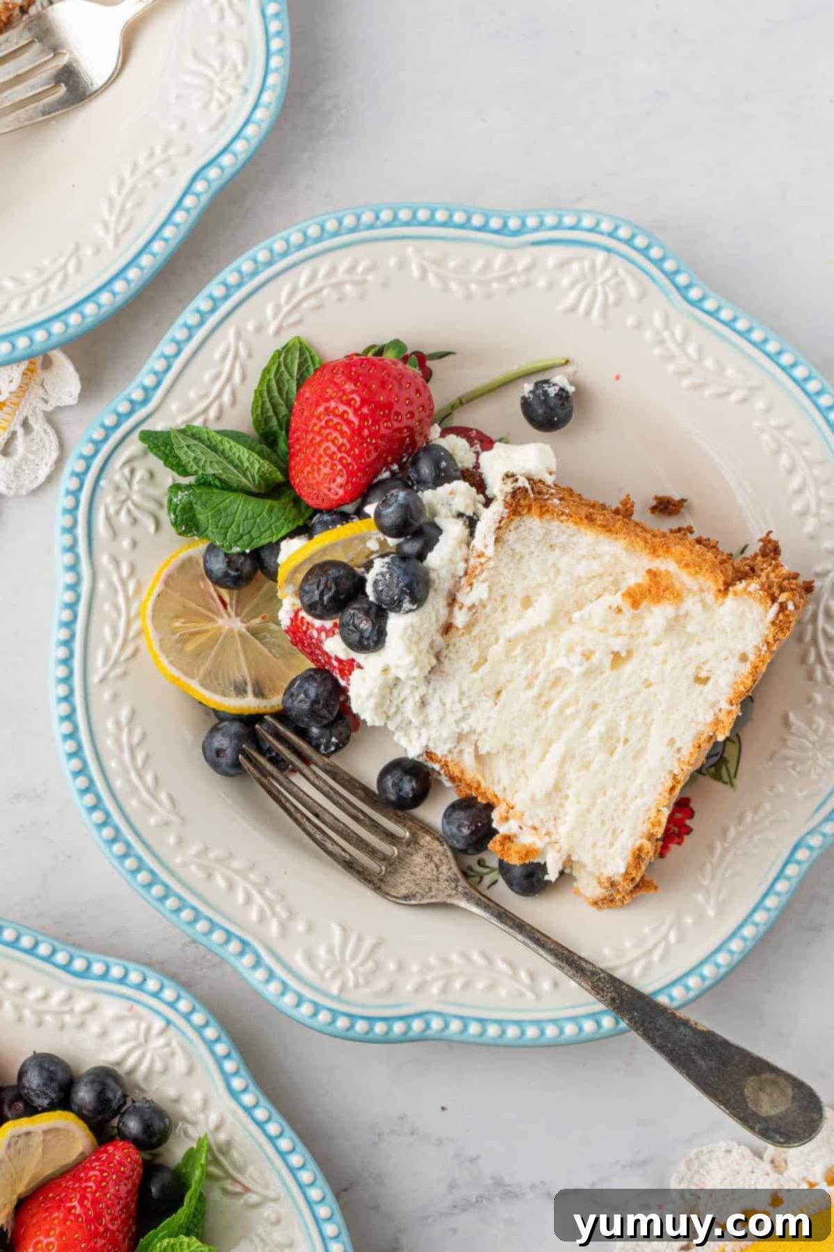 A perfectly baked slice of lemon angel food cake on a white plate, highlighting its soft, inviting texture.