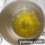 Egg whites in a clean stainless mixing bowl, showing small bubbles forming.
