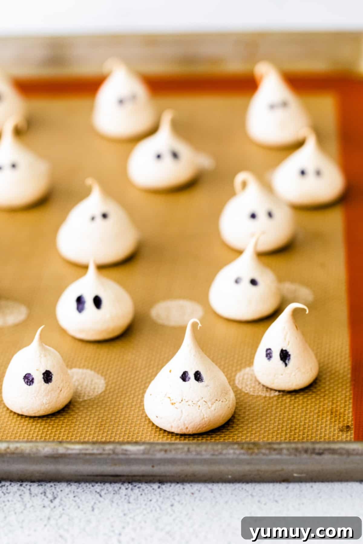 Meringue ghosts on a baking sheet.
