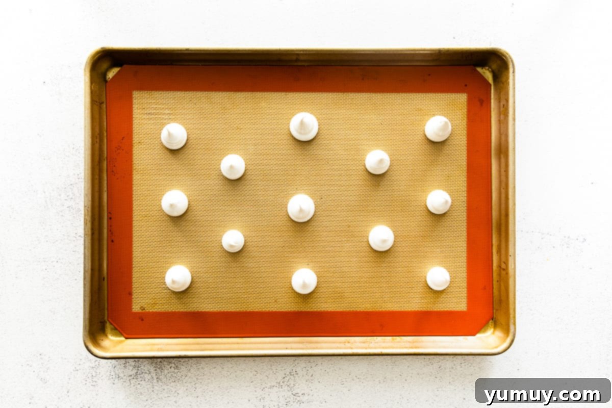 Dollops of meringue batter on a baking sheet.