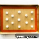 Dollops of meringue batter on a baking sheet.