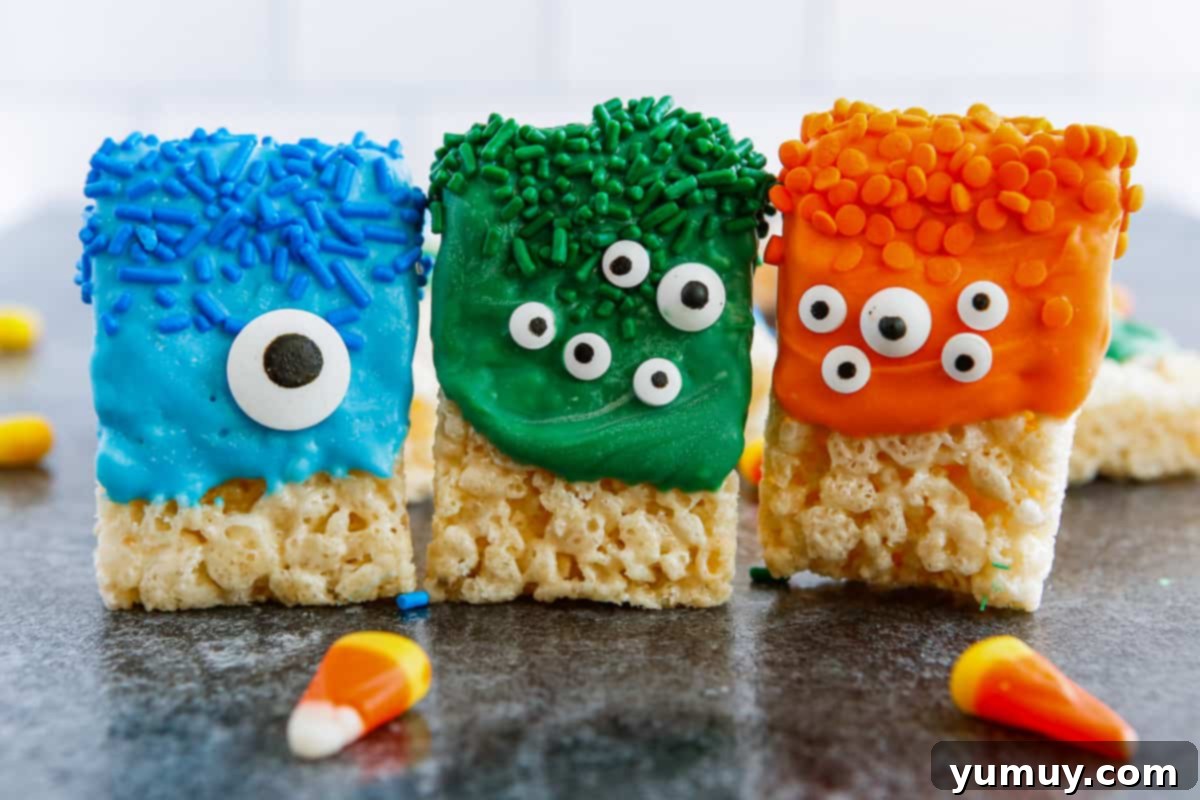 Rice Krispie treats vibrantly decorated with colorful candy melts, a variety of sprinkles, and whimsical candy eyes, laid out for Halloween.