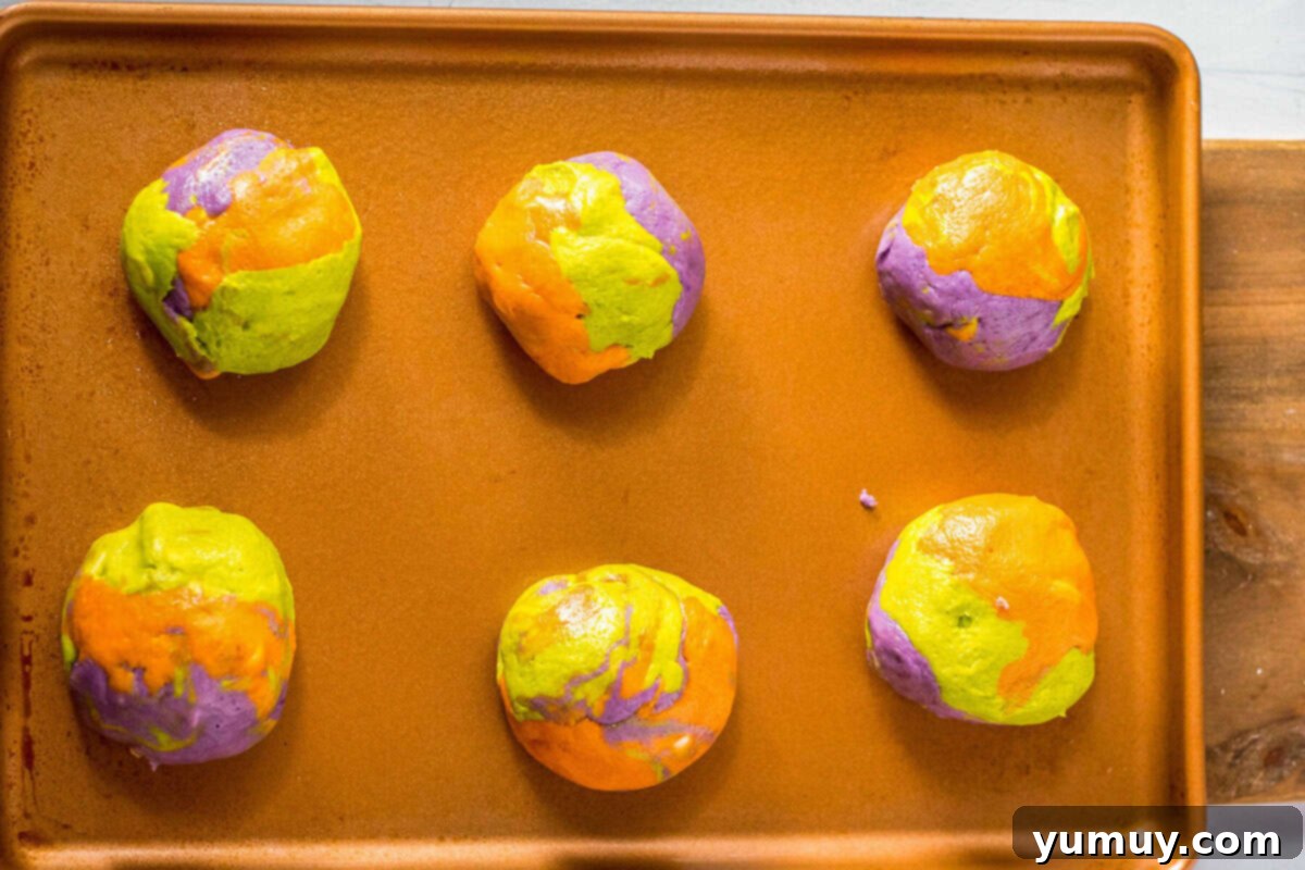 Colorful marbled Halloween cookie dough balls arranged on a baking tray.