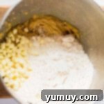 Cookie dough with white chocolate chips being mixed.