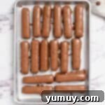 Freshly coated chocolate candy bars, resting on a baking tray to dry and set.