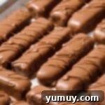 Homemade Twix cookie bars meticulously arranged on a baking tray, chilling until the chocolate sets perfectly.