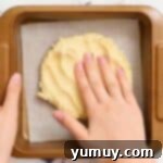 The process of pressing cookie dough firmly and evenly into an 8x8 baking pan.