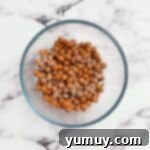 Caramel pieces and heavy cream in a glass bowl, ready to be microwaved for melting.