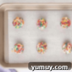 6 funfetti cookie dough balls on a baking sheet.