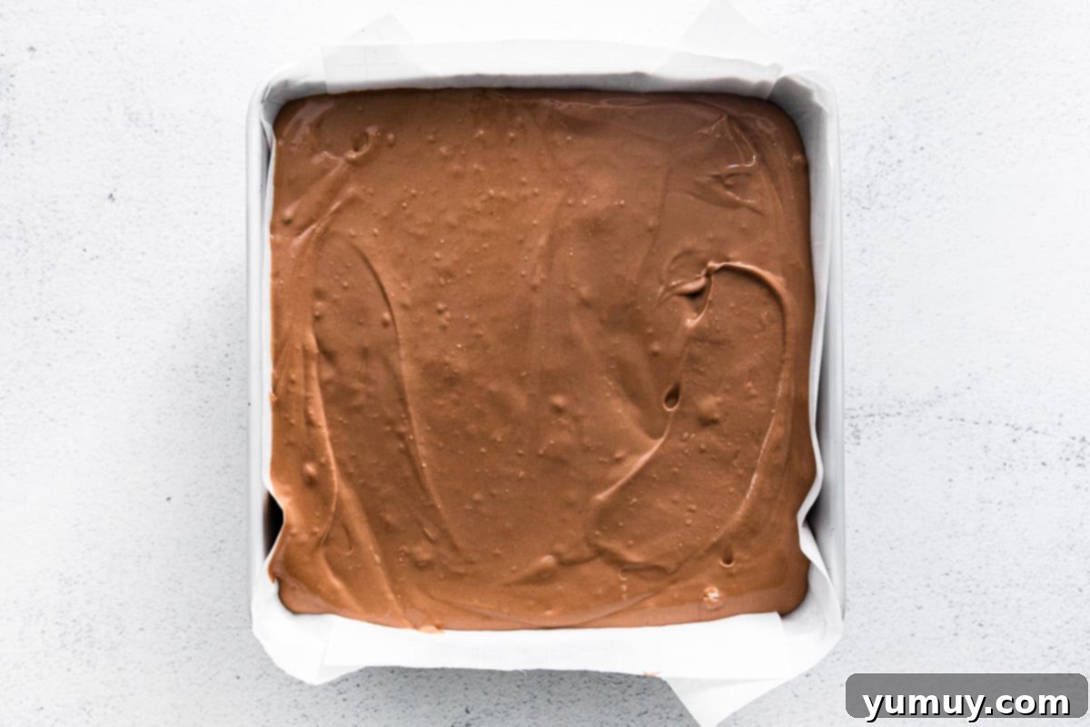 Pouring chocolate cheesecake batter over Oreo crust