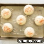 Garnishing pumpkin hot cocoa bombs with white chocolate drizzle and sprinkles.