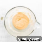 Dry ingredients and smooth pumpkin puree being gently folded into the aerated egg mixture with a rubber spatula.