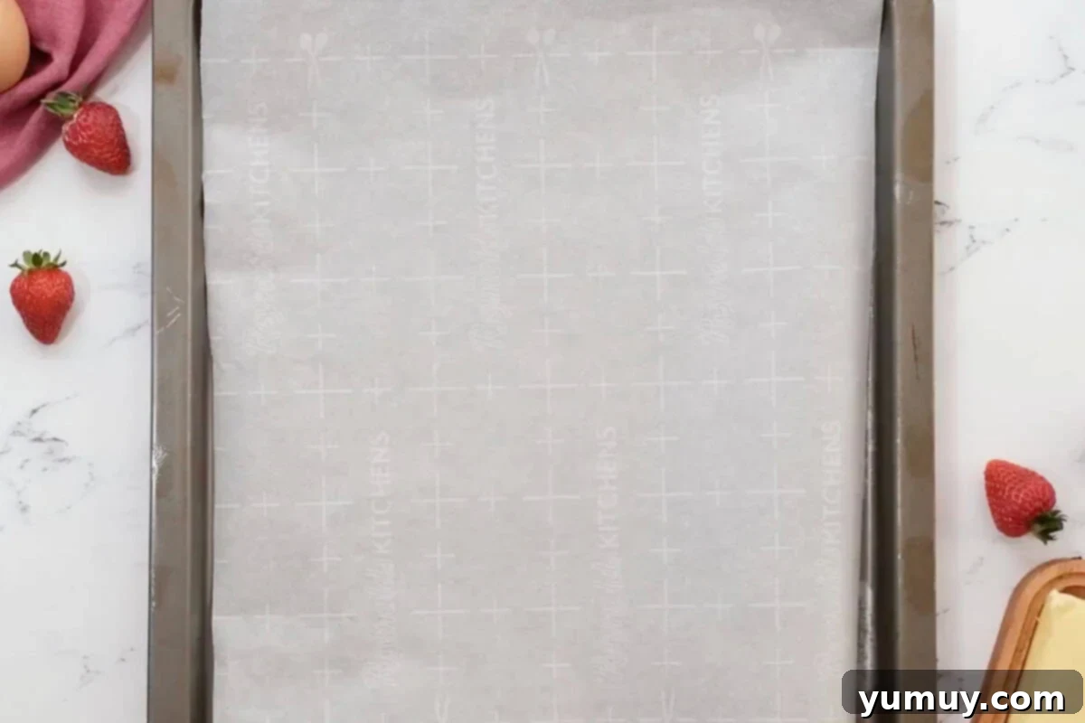 A baking sheet lined with parchment paper, ready for piping cream puffs.