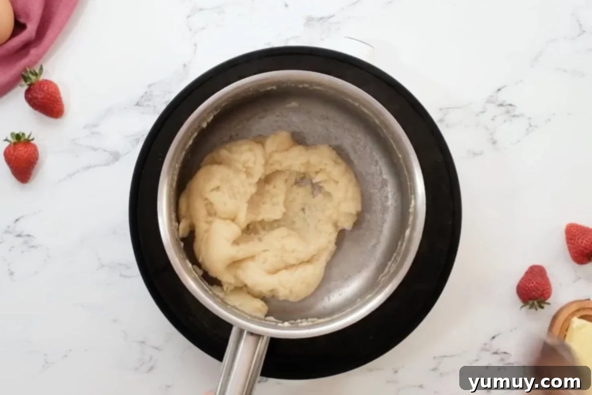 Thick pastry dough in a saucepan after stirring, pulling away from the sides.