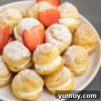 A plate of pastries with strawberries and powdered sugar.