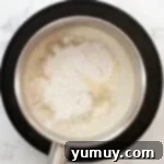Adding flour to melted butter and water in a saucepan.