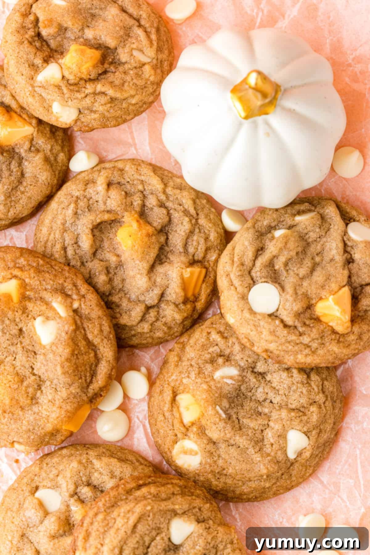 Close-up of freshly baked white chocolate chip pumpkin spice cookies on a pink table, ready to be enjoyed.