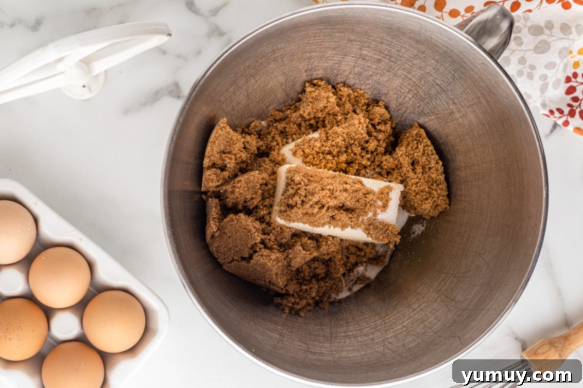 Room temperature butter and brown sugar being creamed together in a mixing bowl using a hand mixer.