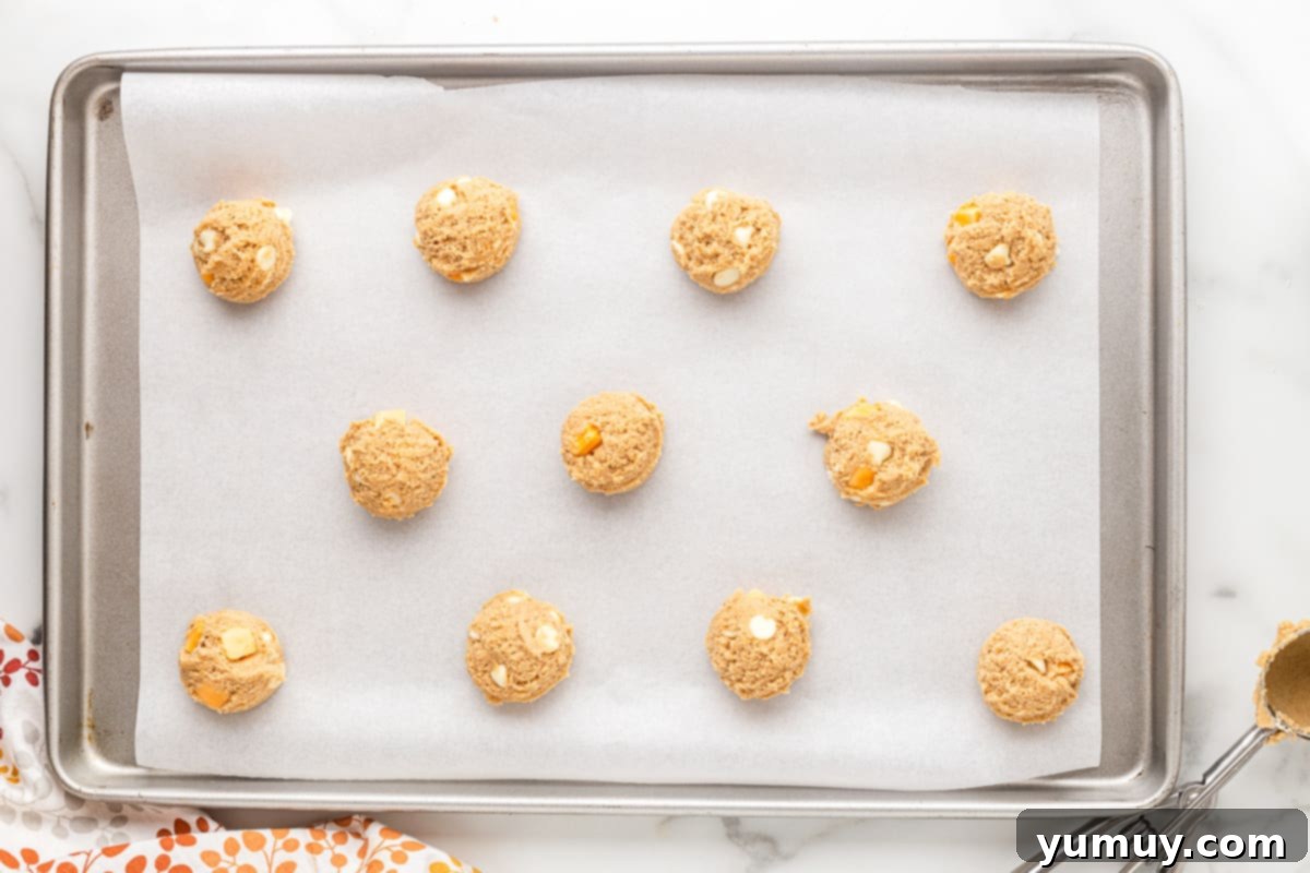 Uniform balls of pumpkin spice cookie dough neatly arranged on a baking sheet, perfectly spaced before going into the oven.