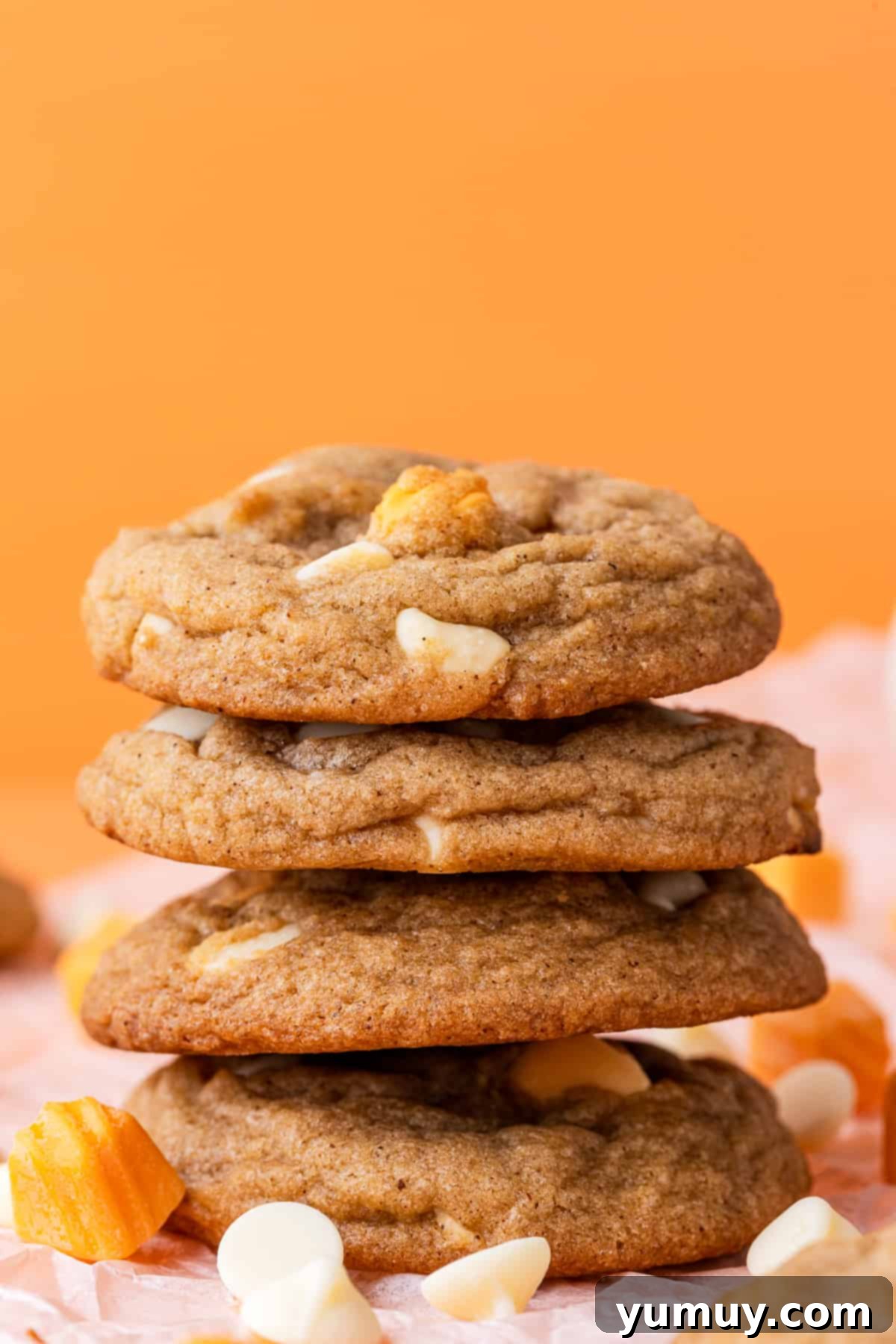 A stack of perfectly baked pumpkin spice cookies filled with white chocolate chips, showcasing their soft texture.