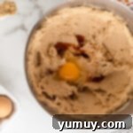 Creamed butter and sugar mixture with eggs and vanilla extract added, being mixed.