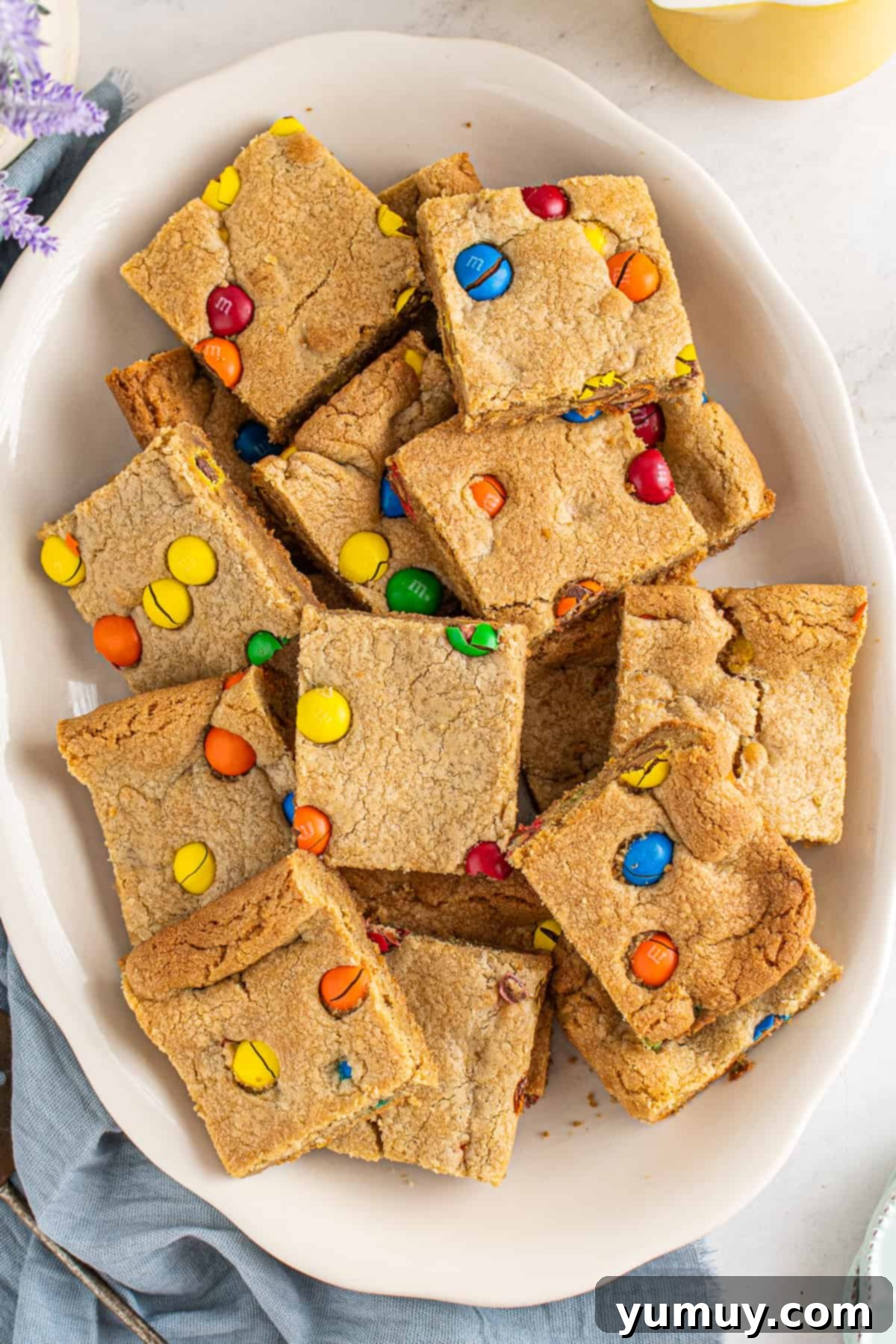 Peanut Butter M&M Blondie Bliss 2 A beautiful platter of freshly baked Peanut Butter M&M Blondies, showcasing their golden edges and colorful candy toppings.