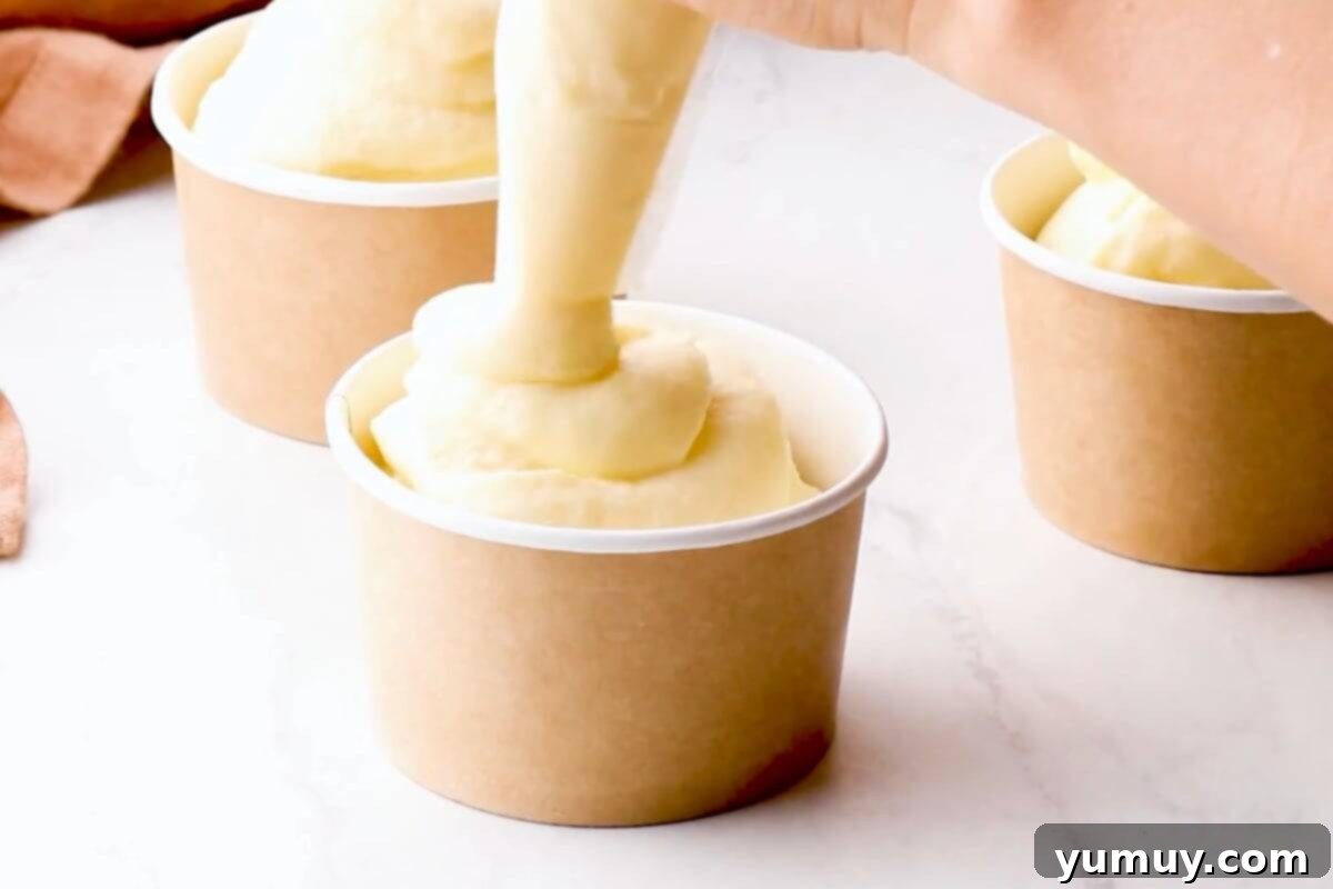 Pineapple Soft Serve Delight 7 piping dole whip into cups.