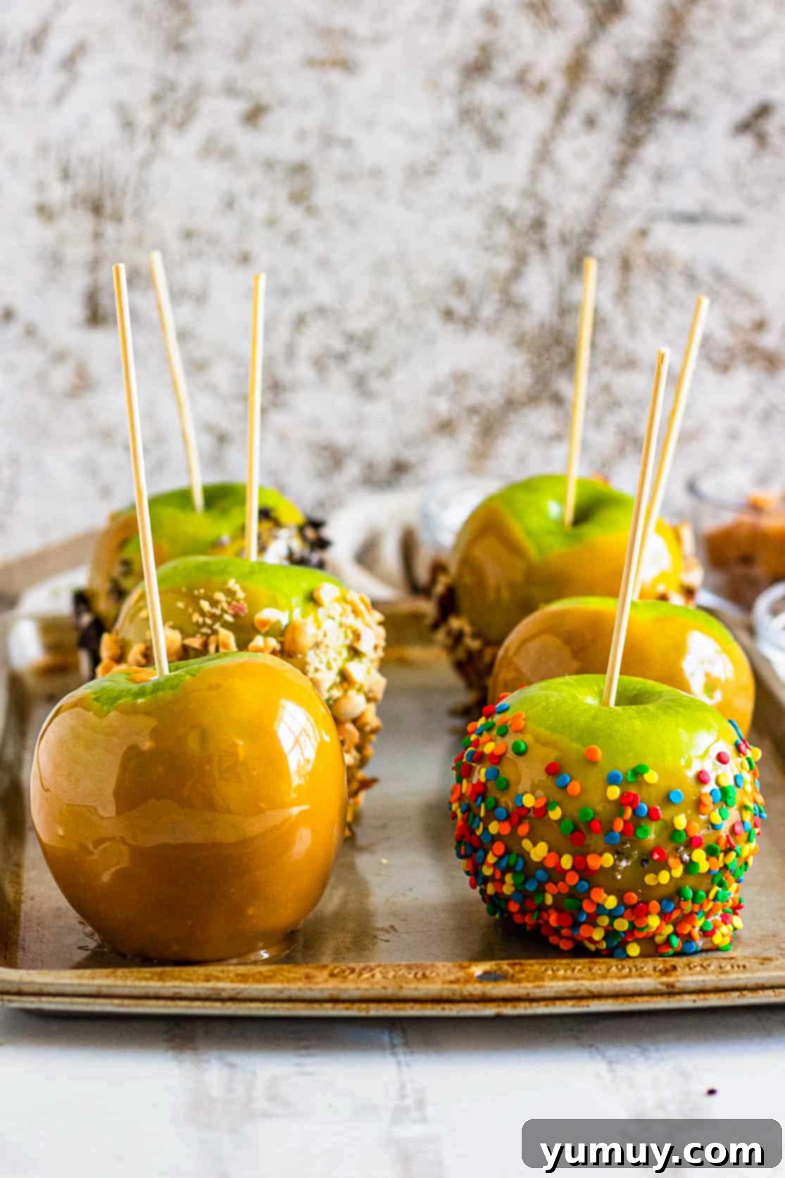Caramel apples on a baking sheet, showcasing their perfect coating and inviting appearance.