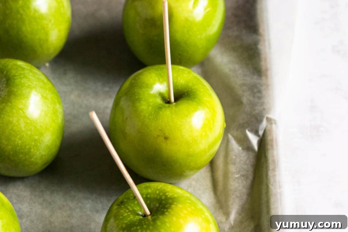 Kebab sticks inserted into the center of apples, prepared for dipping in caramel.