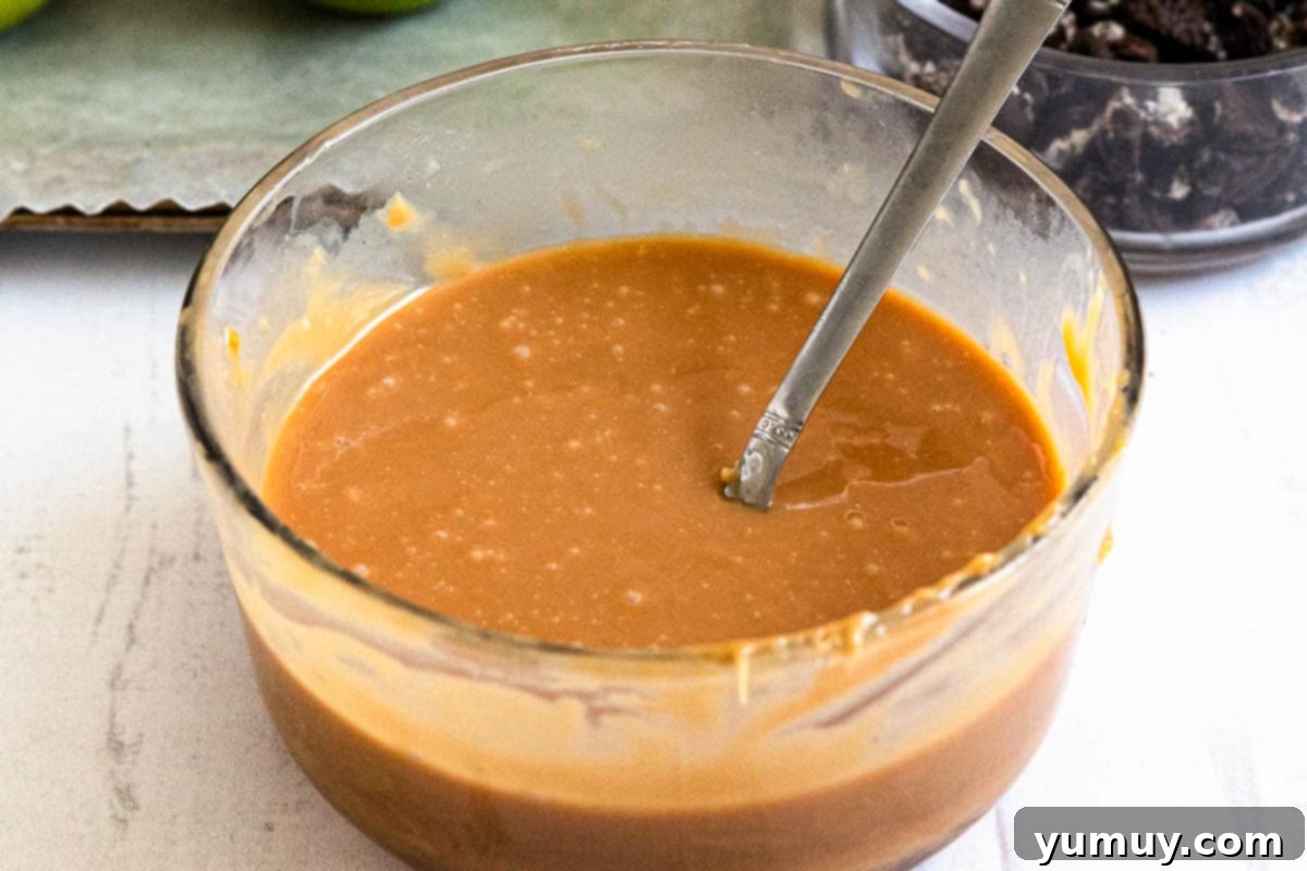 Melted chewy caramels and heavy cream in a microwave-safe bowl, ready for apple dipping.