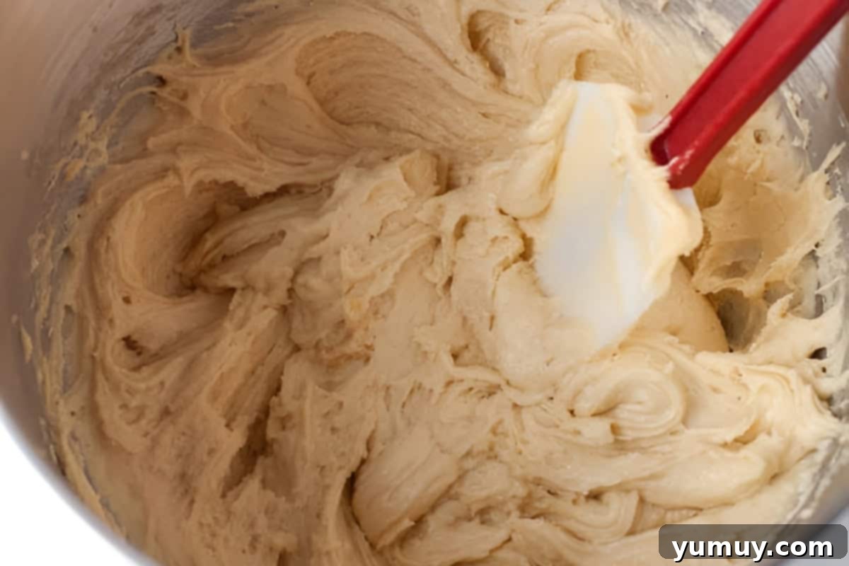 Raspberry Bliss Blondies 10 Almond blondie dough in a stand mixer bowl with a rubber spatula, showing the delicate incorporation of the almonds.
