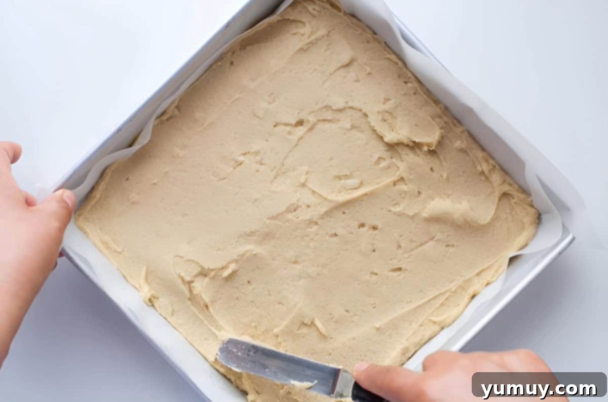 Raspberry Bliss Blondies 11 Spreading blondie dough in a square baking pan with an offset spatula, ensuring an even layer for baking.