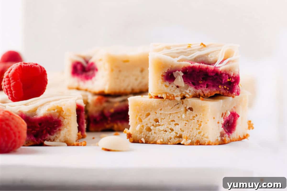 Raspberry Bliss Blondies 3 Side view of stacks of raspberry white chocolate blondies on a marble platter, highlighting their layers of flavor and irresistible appearance.