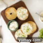 Flavored Cream Cheese: Triple the Deliciousness 8 overhead view of an askew wooden cutting board with 2 halved bagels with flavored cream cheese on top.